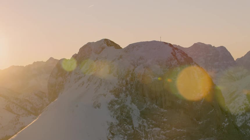 The sun sets over snowy mountains