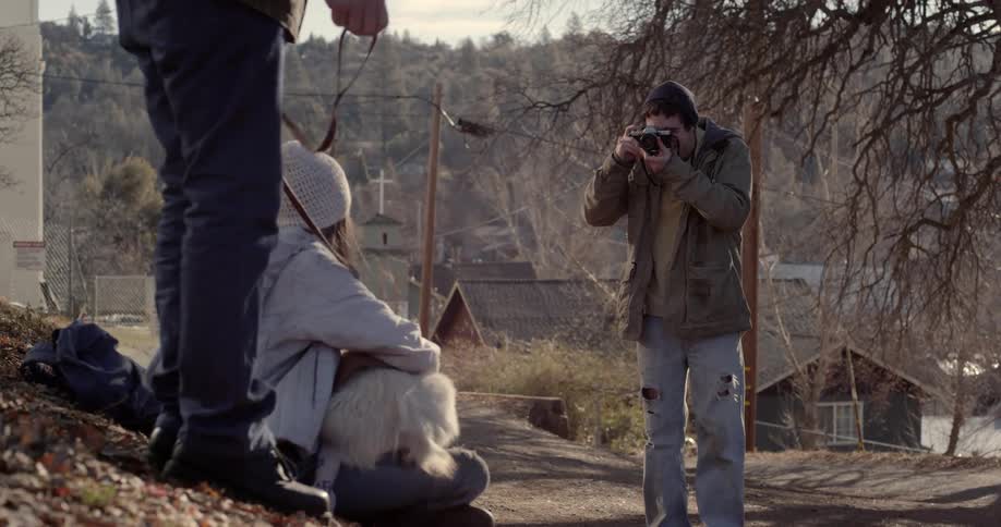 A person is taking a picture of a woman holding a dog