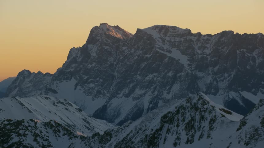 Dusk is settling over a snow-covered mountain range