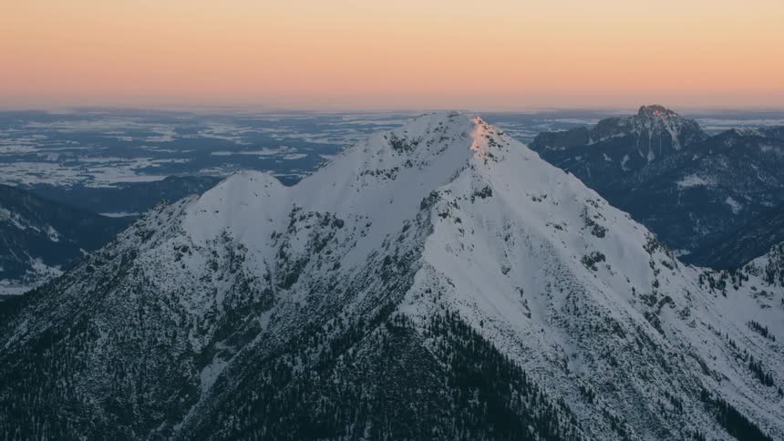 The sun sets over snowy mountains