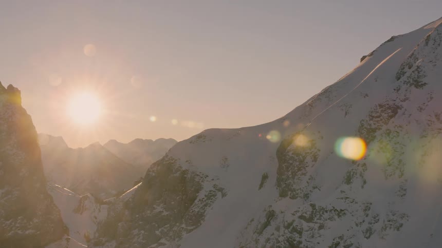 The sun sets over snowy mountains