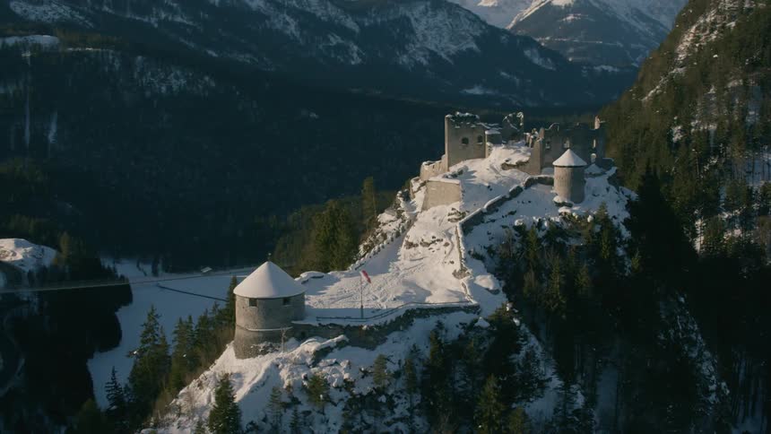 A castle like building sits atop a tree covered hillside