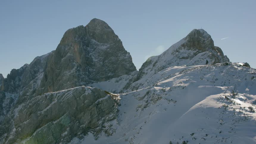 The sun is shining on jagged mountain peaks covered with snow
