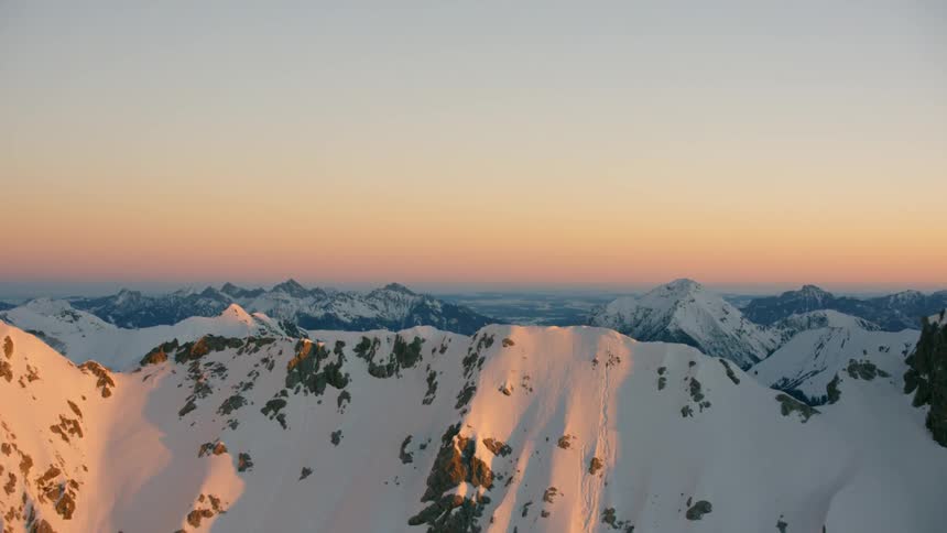 The sun sets over snowy mountains