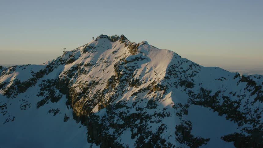 Snow covers a mountain peak at sunset