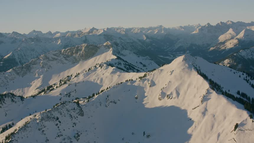 Snow blankets the slopes of a mountain range on a sunny day