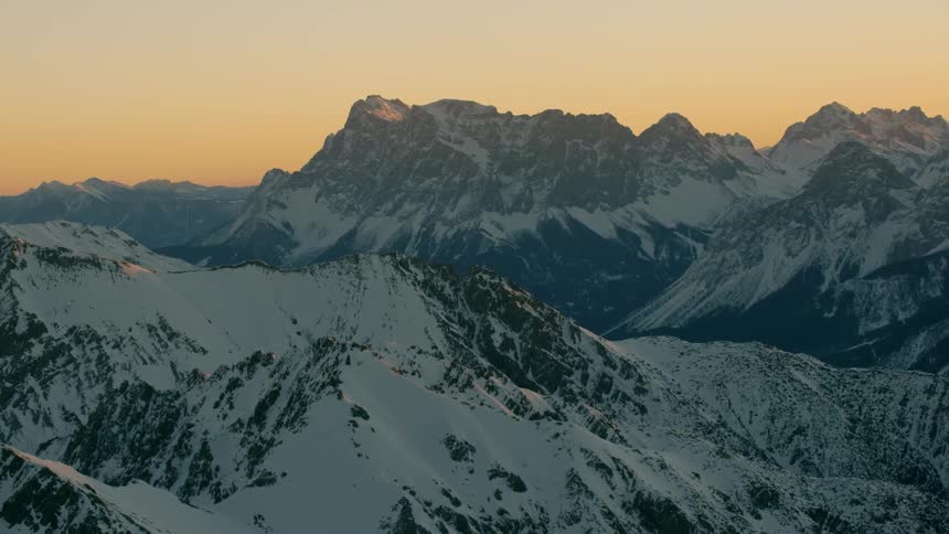 The sky is yellow with the sun setting behind the mountains