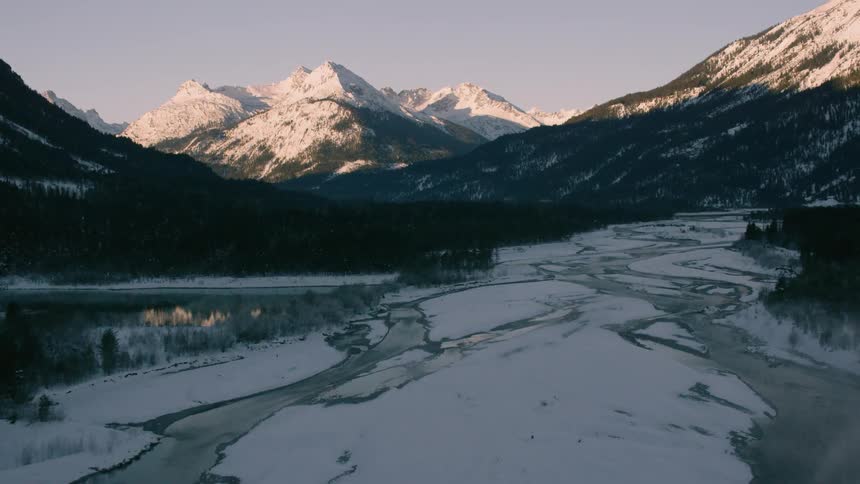 A melting river winds its way through a mountain valley