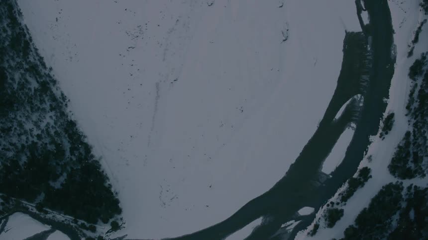 A melting river winds its way through a mountain valley