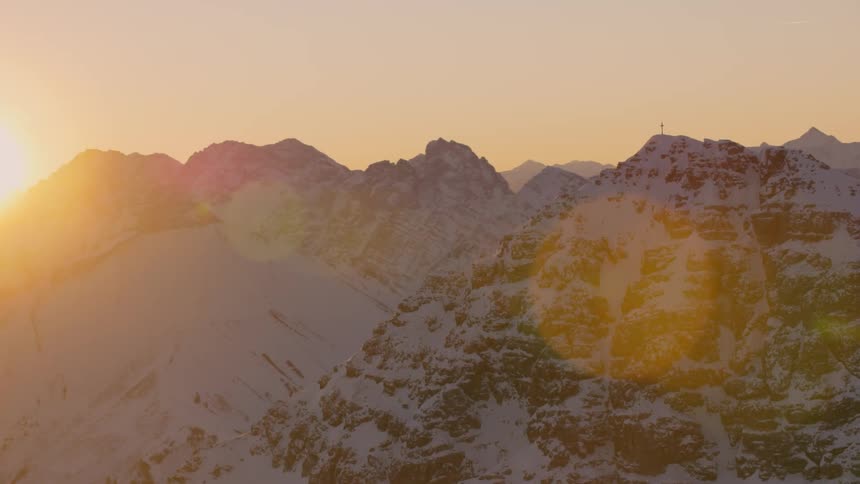 The sun sets over snowy mountains