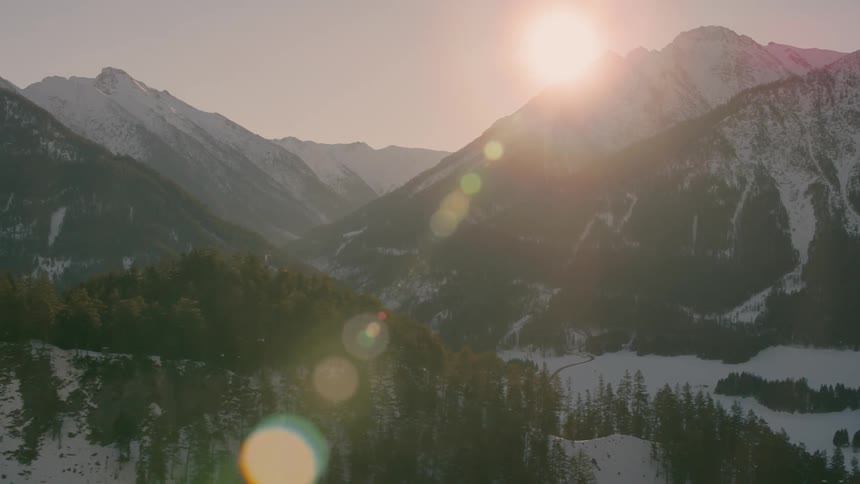 The sun is setting slowly behind the snow covered mountain range