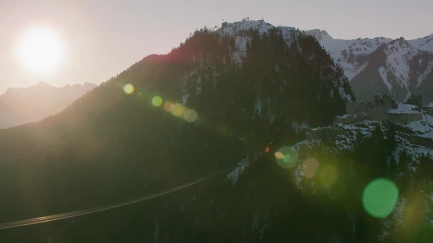The sun shines on tall snowy mountains