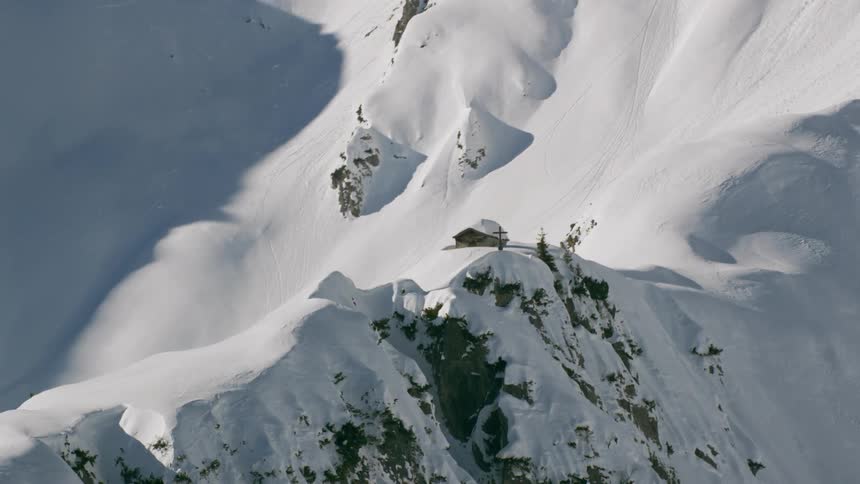 A single house and cross are on the mid section of this mountain