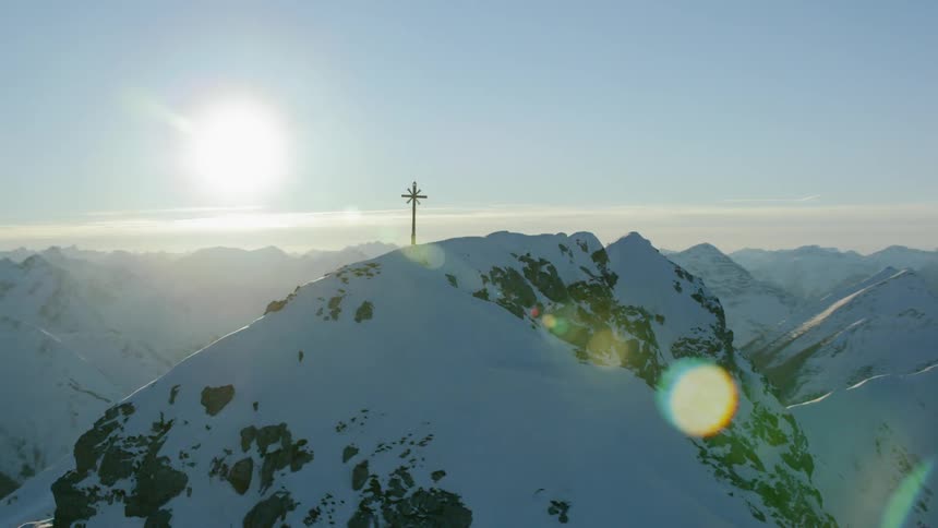 A cross sits atop a snowy mountain