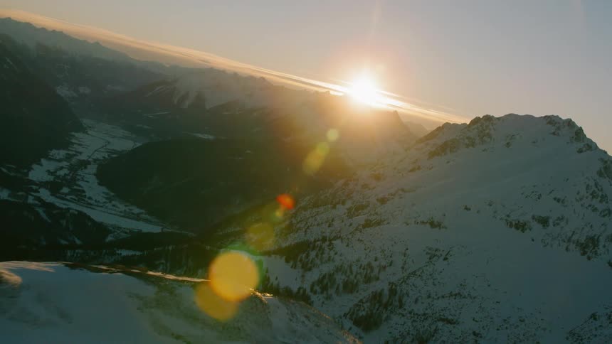 The sun sets over snowy mountains