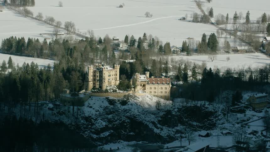 A large building sits atop a snow covered hill