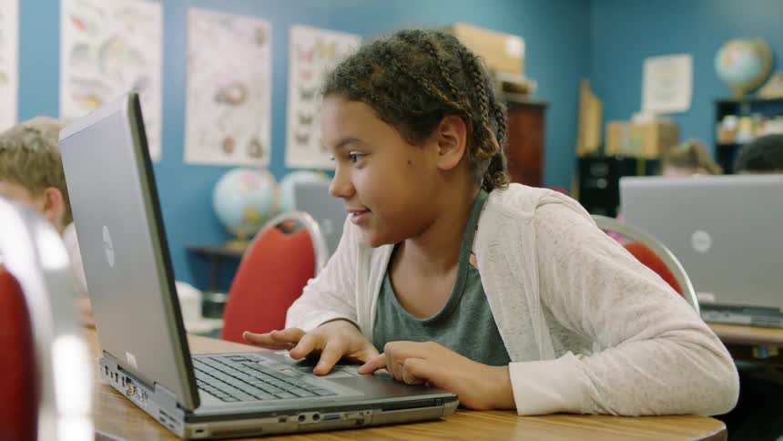 Students work on laptops in a classroom