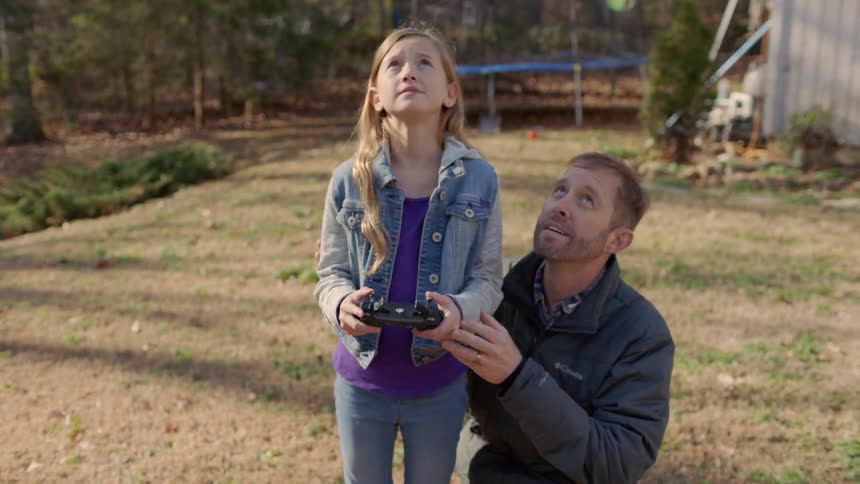 A man and young girl play with a drone