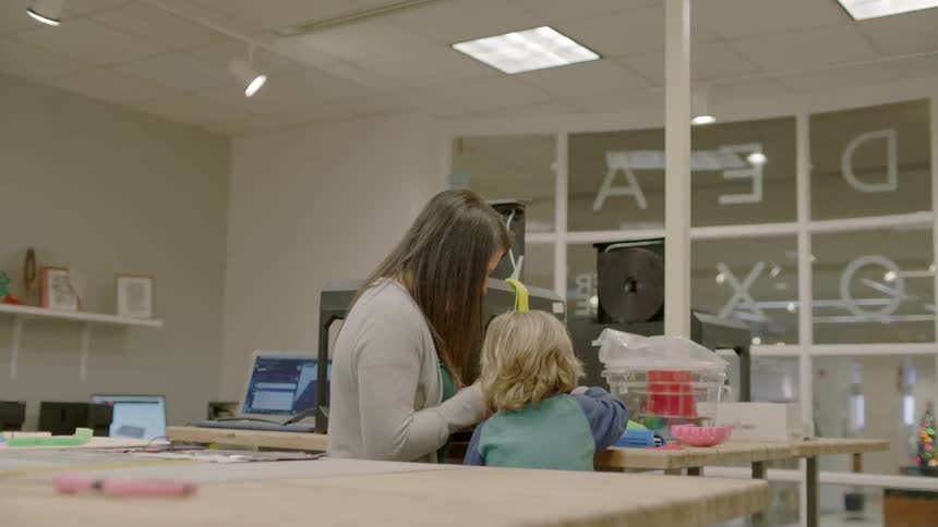 A woman and a small child are sitting together working on something