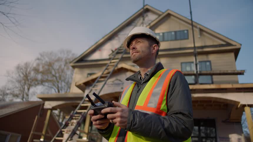 A construction worker holds a controller outside