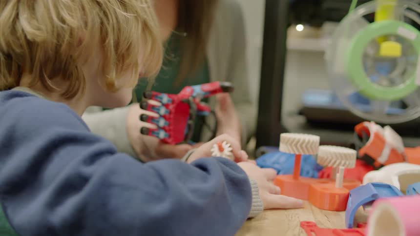 A child is putting together toys on the table with a parent