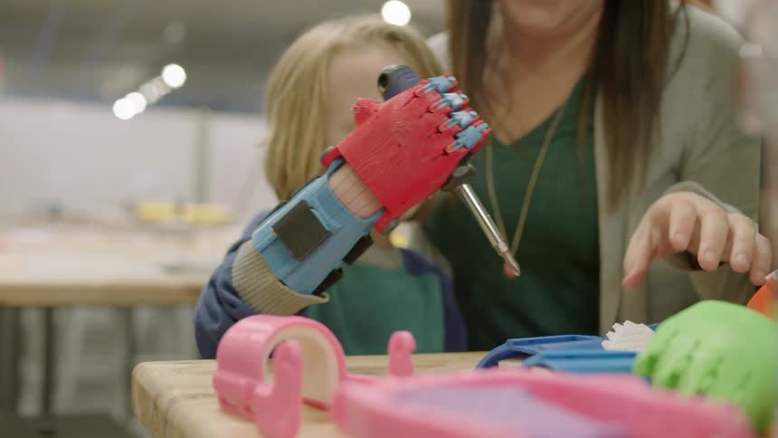 A boy uses a robotic hand