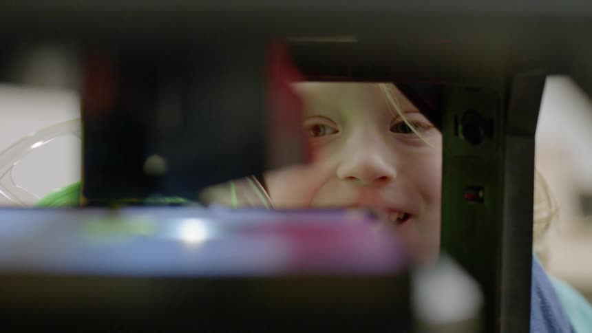 A young boy watches a 3d printer begin to print an object
