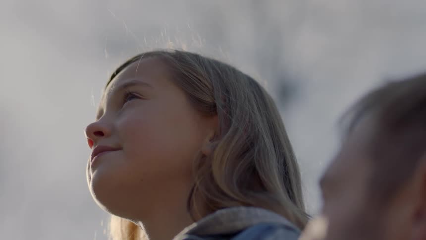 A girl smiles looking up at the semi cloudy sky