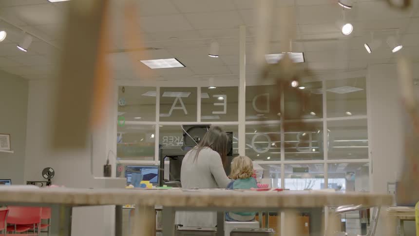 A woman stands next to a boy indoors