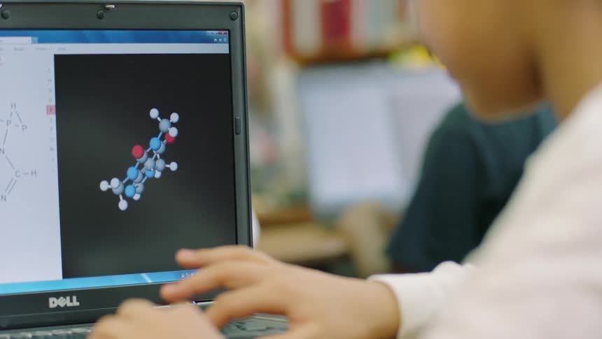 A student in a classroom is looking at a molecular model on a computer