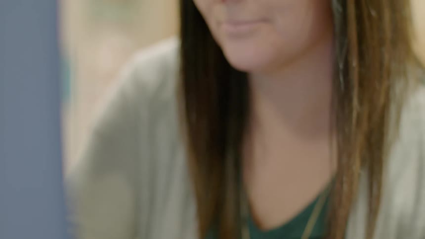 A woman is using a laptop indoors during the day