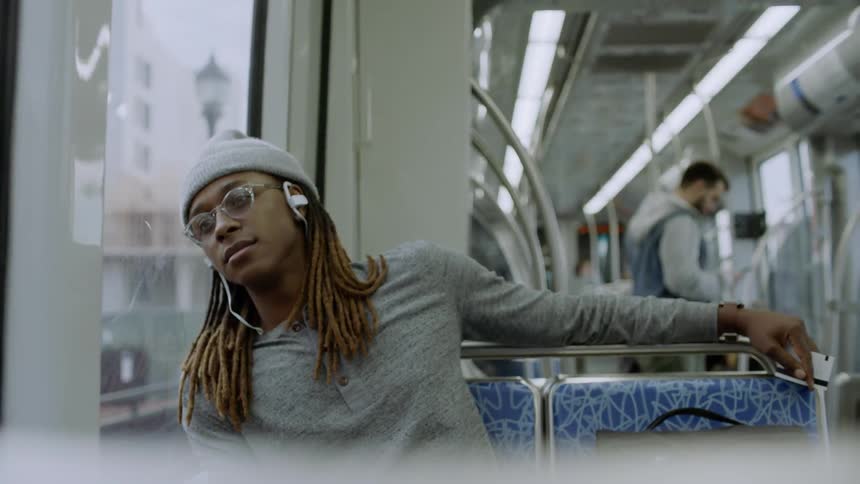 A man listens to headphones while riding public transit