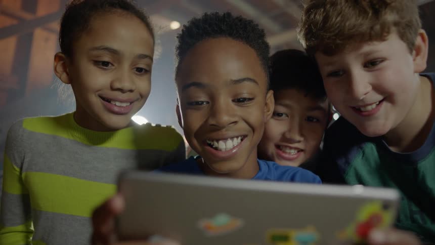A group of children gather around a tablet