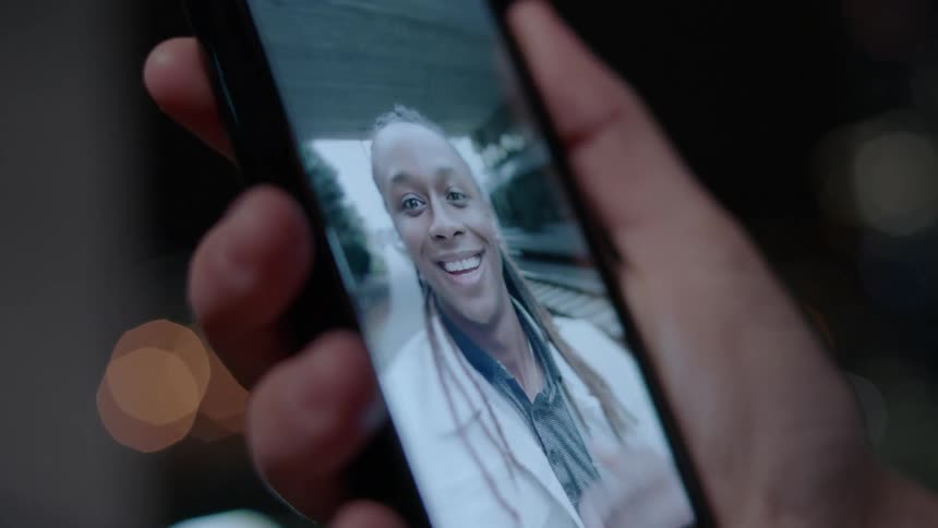 A woman waves from a phone video