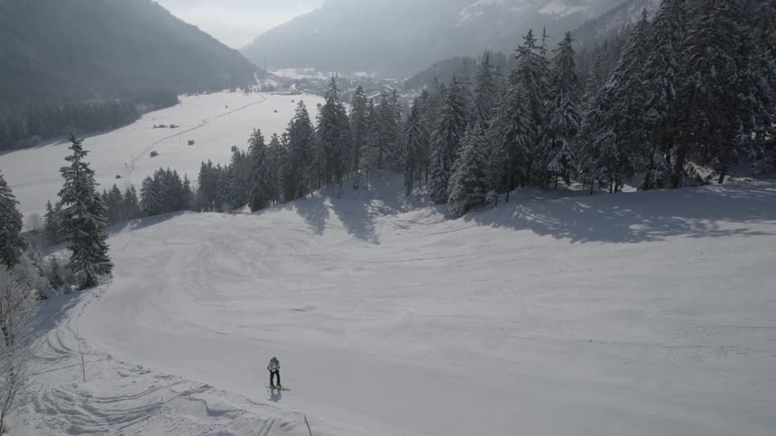 A man is trekking up a mountain slope covered in snow during the day