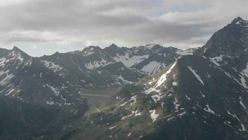 Large mountain range partially covered in snow on cloudy day