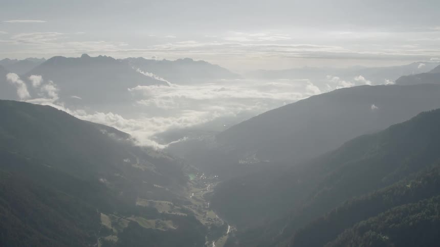 Clouds hover over a mountain valley on a sunny day