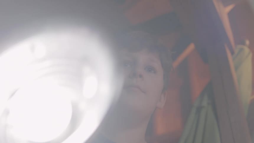 A boy is shining flashlight in a building