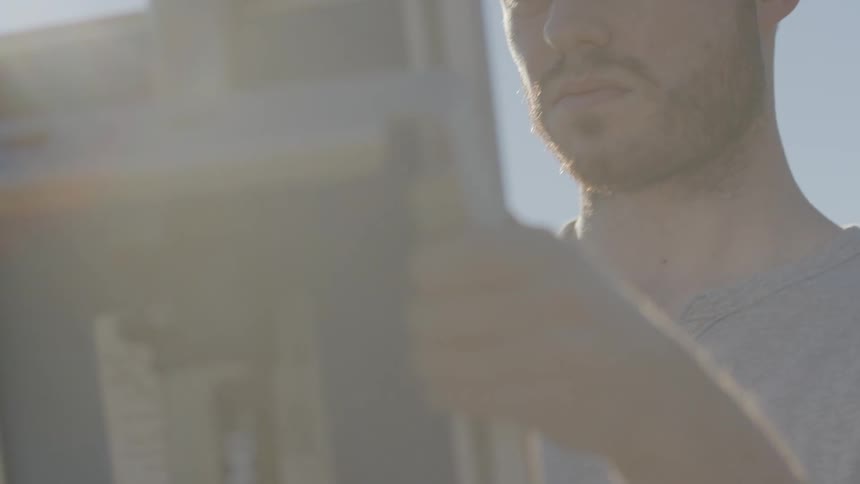 A man is setting up a device under the bright sun