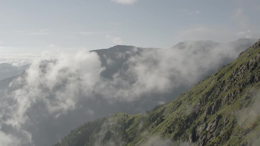 Clouds hover over mountains on sunny day