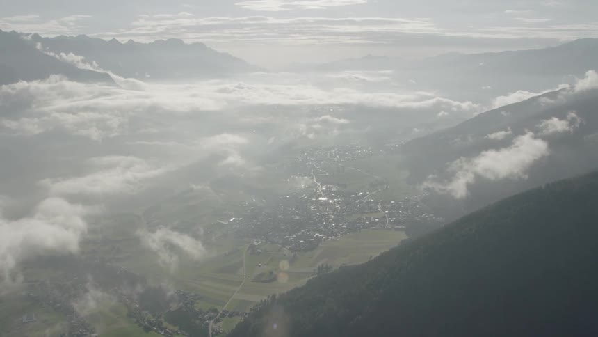 Clouds hover over a mountain valley on a sunny day