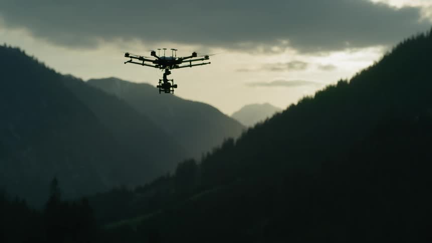 The mountains are dark as the drone lowers below the clouds