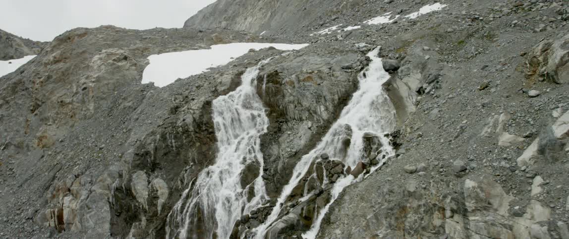 Waterfalls are cascading down a barren mountain slope
