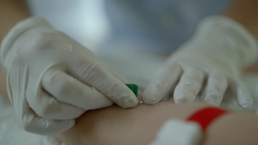 A medical professional inserts a needle into an arm