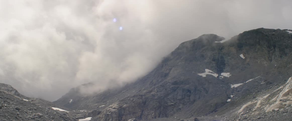 Clouds float over rocky mountains