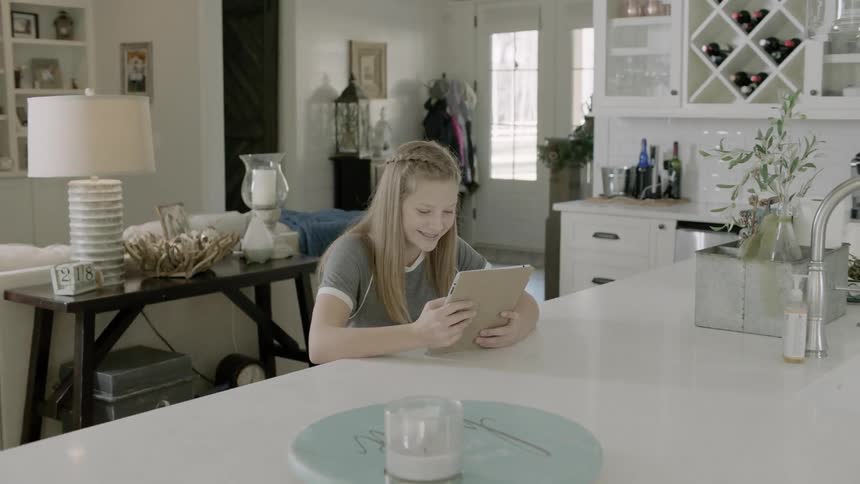 A young girl smiles while using a tablet