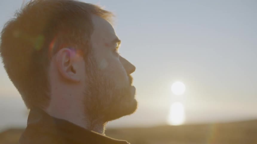 Man stands outside at sunset