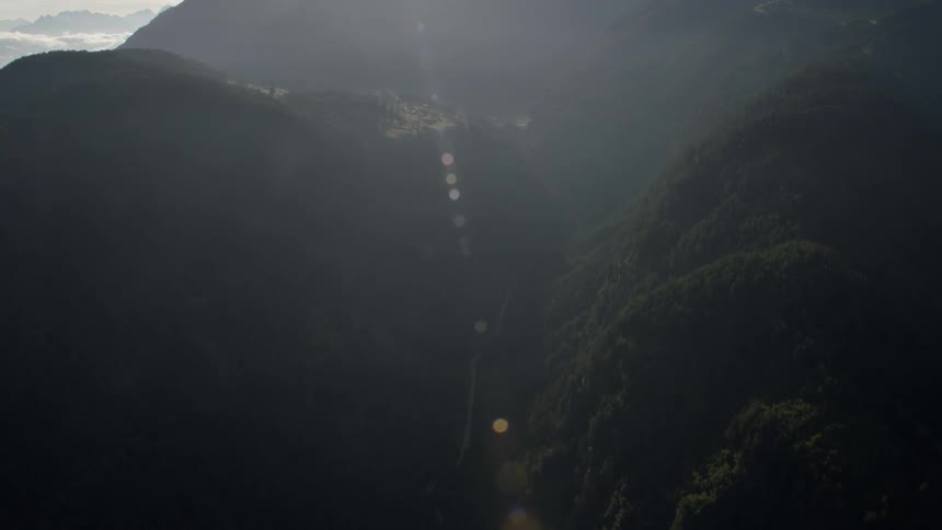 The sun shines between mountains