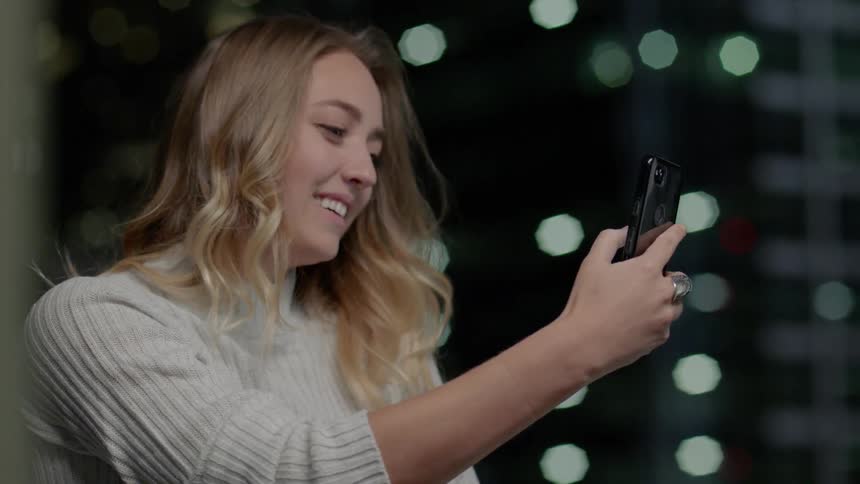 Woman smiles while holding cell phone
