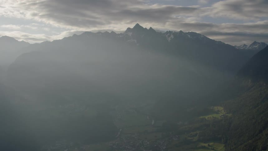 The sun's rays are shining over the tall mountain